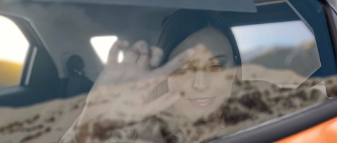 A moça vista de fora pelo vidro do carro