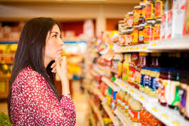 Mulher escolhendo produtos em uma gôndola de supermercado