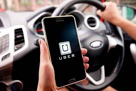 motorista com mão no volante e celular com o Uber